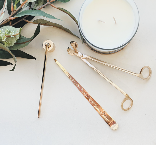 Set of gold and rose gold metal straws on a white surface with a candle and greenery.