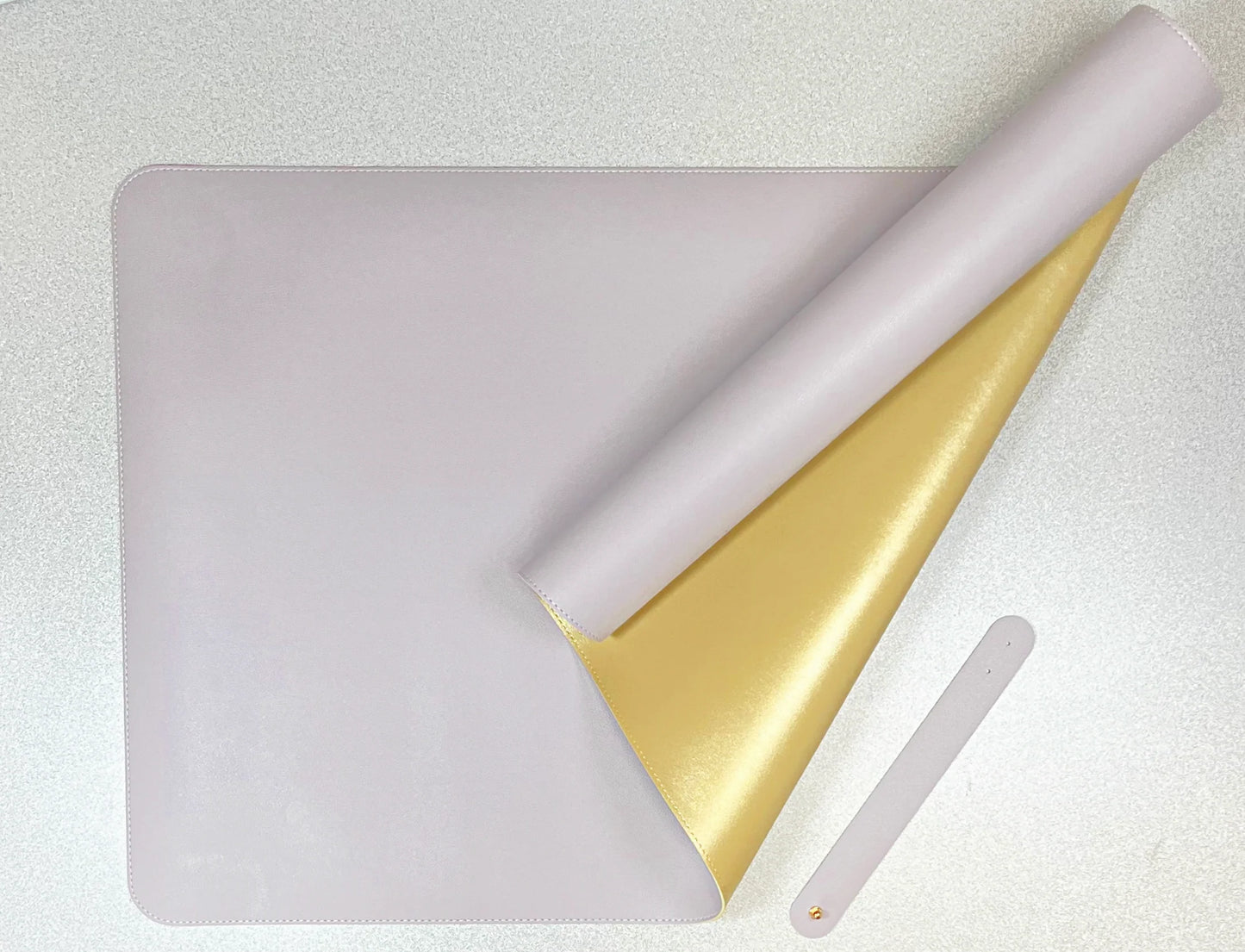double sided desk mat in lavender and gold on a textured white surface