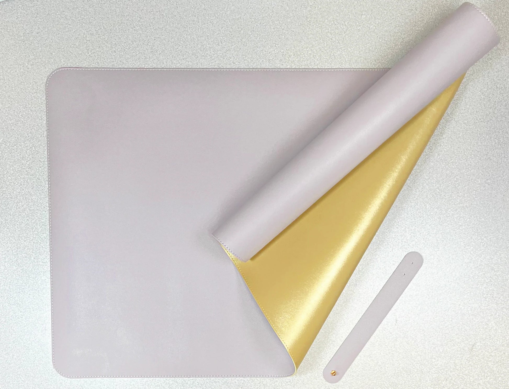 double sided desk mat in lavender and gold on a textured white surface