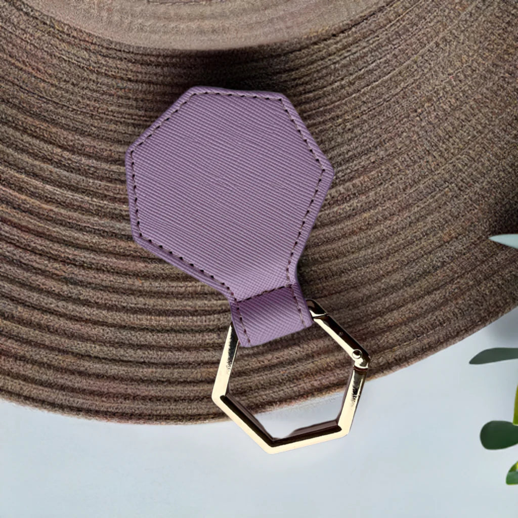 Brown hat with a purple hat clip  gold clasp on a light blue background