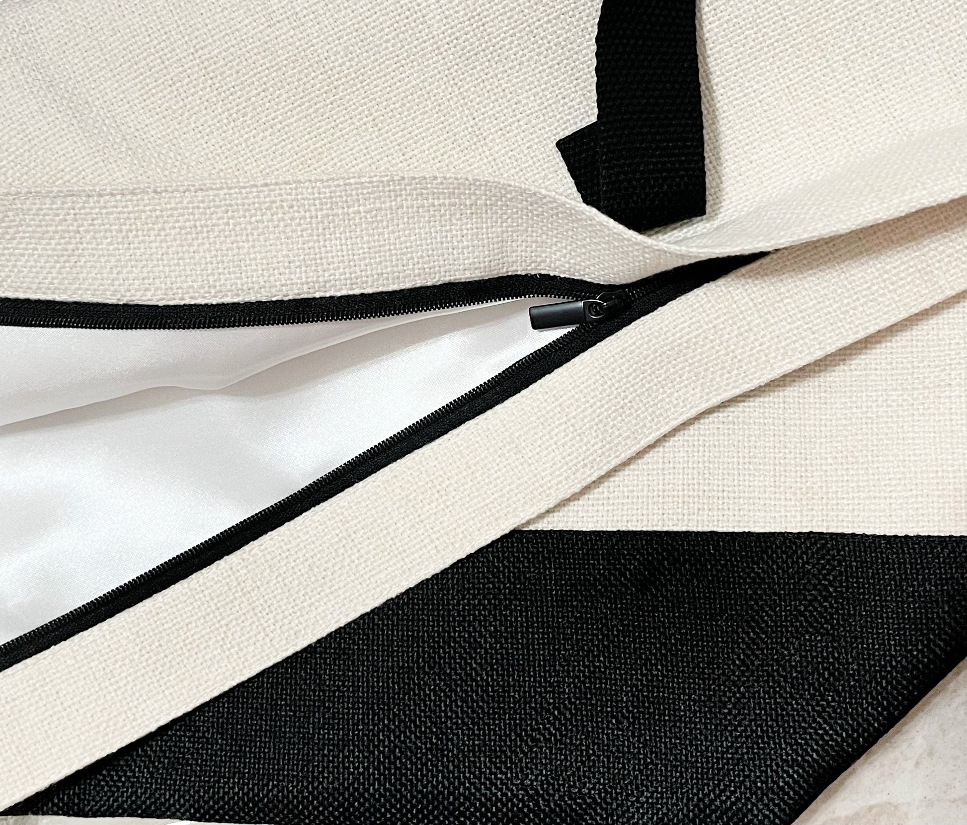 black zipper with white liner on white canvas tote bag with black handels