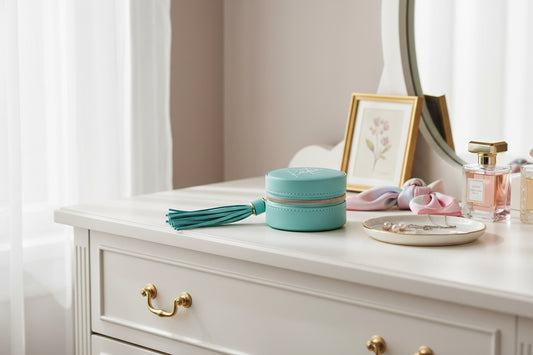Turquoise round jewelry box with tassel and 'kate' one it on a women's dresser
