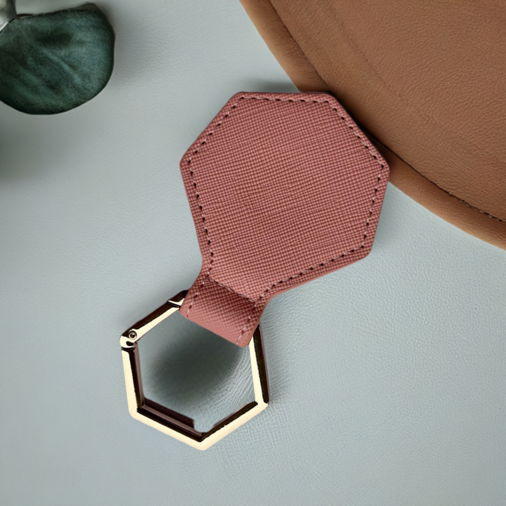 Pink hexagonal hat clip with gold ring on a light gray surface