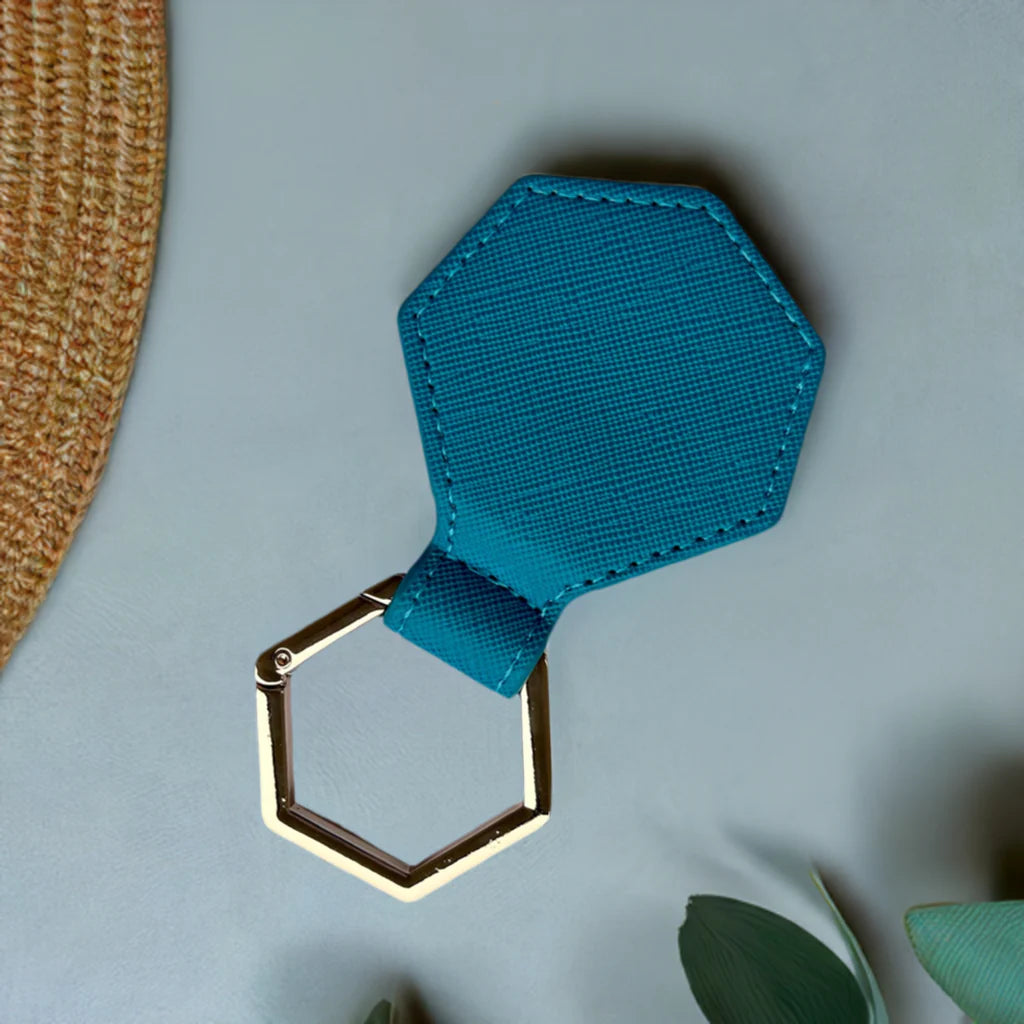 Blue hexagonal hat clip with gold ring on a light gray background
